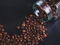 scattered coffee beans from a glass jar on a black background. coffee mood. Royalty Free Stock Photo