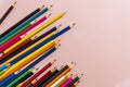 Scattered colored pencils of different lengths on a pink background with a left corner, tending to the center. Horizontal close-up Royalty Free Stock Photo