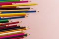 Scattered colored pencils of different lengths on a pink background on the left side, tending to the center. Horizontal close-up Royalty Free Stock Photo