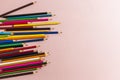 Scattered colored pencils of different lengths on a pink background on the left side, tending to the center. Horizontal view Royalty Free Stock Photo