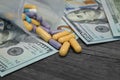 Scattered Colorful Pills and Capsules on Money on Wooden Table Royalty Free Stock Photo