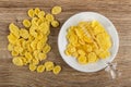 Scattered cornflakes, honey dipper on corn flakes with honey in saucer on table. Top view Royalty Free Stock Photo