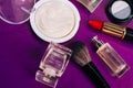 Scattered cosmetics on a purple background. The contents of women`s handbags. Lady set. Lipstick, perfume and shadow. View from Royalty Free Stock Photo