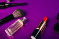 Scattered cosmetics on a purple background. The contents of women`s handbags. Lady set. Lipstick, perfume and shadow. View from Royalty Free Stock Photo