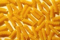 Scattered dried. spiral Italian pasta or noodles on yellow Royalty Free Stock Photo