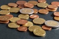 Scattered euro coins on black table close-up. Soft focus