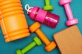 Scattered fitness objects, dumbbells, bricks and bottle on the mat in the gym