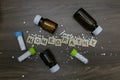 Scattered globules with homeopathy substance bottles and text Homeopathy on wooden background