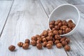 Scattered hazlenuts with white bowl on wood table Royalty Free Stock Photo