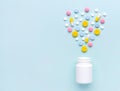 Scattered medicine pills and white container at blue background. Royalty Free Stock Photo