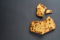 Scattered pieces of tasty sweet homemade bread with raisin lies on dark concrete table in kitchen Royalty Free Stock Photo