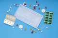 Scattered pills, ampoule blisters and syringe and a medical mask on a blue background Royalty Free Stock Photo