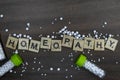 Scattered pills with homeopathic medicine bottles and text Homeopathy on wood background Royalty Free Stock Photo