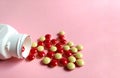 Scattered red and yellow pills with pill bottle on pink background. medical concept Royalty Free Stock Photo