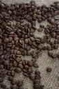 Scattered roasted coffee beans on burlap. Close-up. Vertical Royalty Free Stock Photo