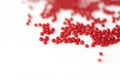 Scattered seed beads red color on a white surface Royalty Free Stock Photo