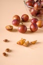 Scattered sliced half ripe sweet plum fruits with water drops near to plums in glass bowl, on cream colored background Royalty Free Stock Photo