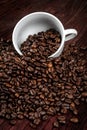 Scattered on the table beans of roasted coffee in a white cup. Morning. Cheerfulness Royalty Free Stock Photo