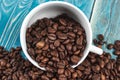 Scattered on the table beans of roasted coffee in a white cup. Morning. Cheerfulness Royalty Free Stock Photo