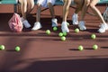 Scattered Tennis Balls On Court By Feet Of People