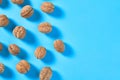 Scattered whole ripe walnuts on blue background. Copy space