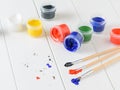 Scattered on a wooden table jars of gouache and three multi-colored brushes. Creative kit. Royalty Free Stock Photo