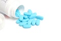 Scattering blue pills from bottle on white background