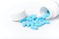 Scattering blue pills from bottle on white background