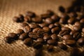 A scattering of coffee beans on a dark burlap background