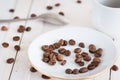 Scattering coffee beans on a saucer cup and spoon in the background surface