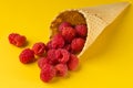 A scattering of fresh juicy natural raspberries in a waffle cone for ice cream. Minimalism on a yellow bright background. Healthy Royalty Free Stock Photo