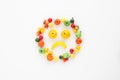 A scattering of many small different fruits on a white background. Emoji sad smile. Minimalism.