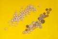 A scattering of pills near a placer of coins on a yellow background. The concept of the high cost of medical drugs. Flat lay Royalty Free Stock Photo