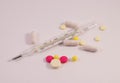 A scattering of pills on the table and a thermometer Royalty Free Stock Photo