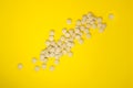 Scattering of pills on a yellow background. Natural food supplement brewer`s yeast with vitamins and microelements. Flat lay.