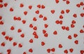 A scattering of red small hearts on a white background, a festive gift of love and the concept of Valentine`s Day. Little hearts Royalty Free Stock Photo