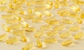 A scattering of transparent yellow oval omega-3 capsules