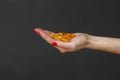 Scattering of transparent yellow pills. Handful of capsules in palm of hand, close-up, isolated on gray background