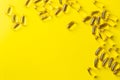 a scattering of yellow transparent fish oil capsules on a yellow background.