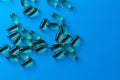 a scattering of yellow transparent fish oil capsules on a blue background.