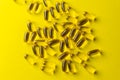 a scattering of yellow transparent fish oil capsules on a yellow background.