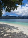 The scene on the beach of an island with turquoise water and blue sky with white clouds Royalty Free Stock Photo