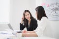 Scene of 2 beautiful asian business women talking and discussing happily in the white meeting room or office, happy working