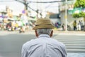 a scene behind an old Asian man wearing a shirt and a felt cap, looking out at the blurred street scene