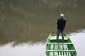 Scene Of Fisherman With His Back Towards Camera Fishing From The Boat On The Calm Lake Royalty Free Stock Photo