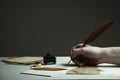 Scene with a man`s hand writing a letter or story with vintage quill and old pieces of paper on white table - with copy space for