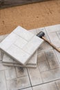 Scene of an ongoing pavement or tile installation. There is a rubber mallet and tiles on top of the partially completed pavement,