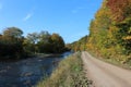 A dirt road in autumn in Cape Breton along the Margaree river with the leaves beginning to change on a sunny day Royalty Free Stock Photo