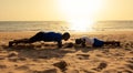 Scene of silhouette of father and his son doing musculation sport on sand at beach during sunset in Africa, Senegal