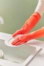 Scene with a woman washing dishes in the kitchen wearing orange rubber gloves, clean background